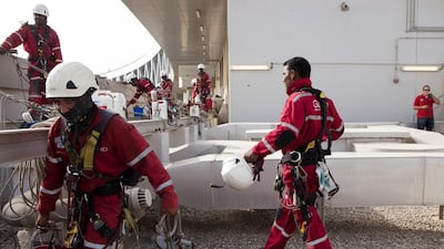 Before the workers start their descent, a site manager checks knots and each harness to ensure everything is in order, and offers adjustment tips when needed. Christopher Pike / The National