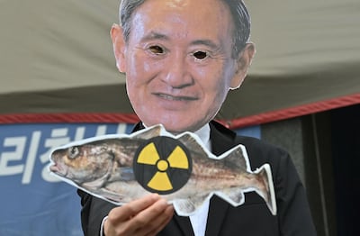 A South Korean environmental activist wearing a mask of Japan's Prime Minister Yoshihide Suga holds a picture of a fish with a radioactivity warning sign during a protest against Japan's decision on releasing Fukushima wastewater, near the Japanese embassy in Seoul. AFP