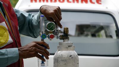 An aid worker of the Alamgir Welfare Trust in Islamabad fixes a regulator on an oxygen cylinder before it is delivered to a Covid-19 patient. Imran Mukhtar/ The National