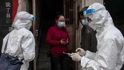 Civil servants check a local resident for her negative Covid-19 test results before allowing her outside, in the Jordan district in Hong Kong, China. EPA