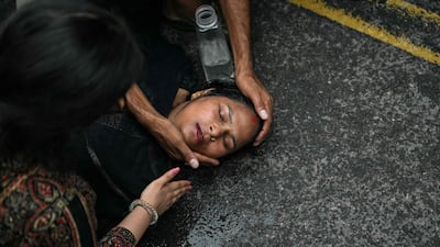 People assist a woman who fainted during a clash with police at a protest demanding the resignation of India's Education Minister, in New Delhi. AFP