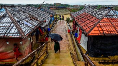 A Rohingya refugee girl shelters from the rain under an umbrella as she makes her way back home after collecting relief aid at the Kutupalong Rohingya refugee camp in Bangladesh's Ukhia district on August 24, 2019. / AFP / MUNIR UZ ZAMAN