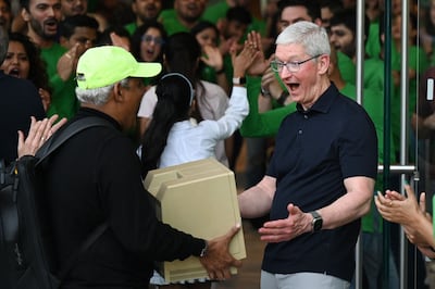 Apple's Tim Cook reacts as a man shows him an older Macintosh.
