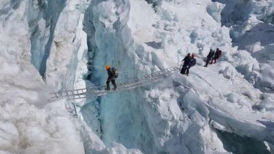 Members of the Armed Forces cross a crevasse on ladders in the Khumbu Icefall.