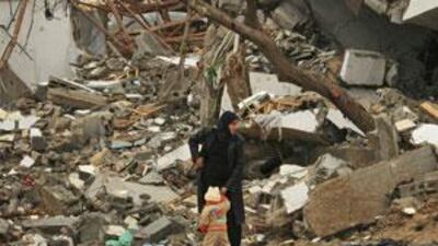 A Palestinian woman and her child walk in front of a destroyed house in Rafah, in the southern Gaza Strip.