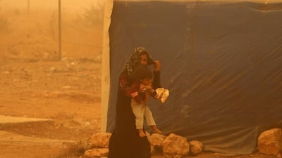 A Syrian refugee and her child walks outside their tent at a camp near the eastern Lebanese city of Baalbek. AFP Photo