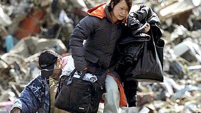 A woman carries belongings she collected from a house swept by a tsunami at Rikuzentakada, in northeastern Japan.