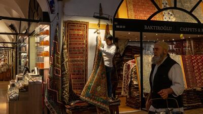 There are few shoppers in sight as a trader hangs carpets outside his store in the Grand Bazaar in Istanbul