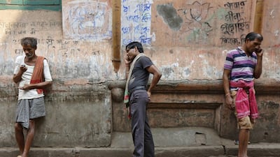 Labourers speak on mobile phones opposite a public call office (PCO) in a market area.