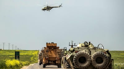 A Russian air force Mil Mi-28 military helicopter flies over Turkish and Russian armoured infantry vehicles driving as part of a joint Turkish-Russian military patrol in the countryside of the Syrian town of Darbasiyah near the Turkish border in the north-east province of Hasakah, on April 22, 2020. AFP