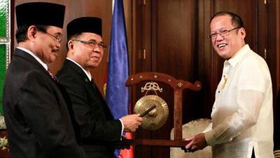 Moro Islamic Liberation Front (MILF) Chairman Murad Ebrahim, centre, signs the peace accord with Philippines president Benigno Aquino III.