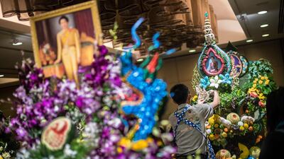 A Thai man helps put together an elaborate decoration with carved fruits and vegetables adorned with images of Thai Queen Sirikit, during a fruit and vegetable carving competition in Bangkok. Robert Schmidt / AFP