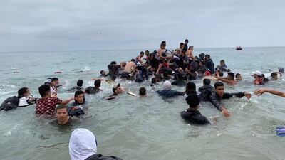 Migrants manage to grab onto a boat of the Moroccan authorities near the coast of Fnideq in an attempt to cross over to Ceuta. EPA