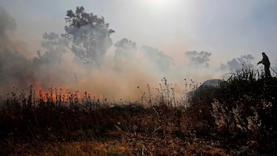 An Israeli extinguishes flames in a burning field next to Kibbutz Beeri reportedly caused by inflamable material attached to kites and flown across the border to Israel from the Gaza Strip. AFP