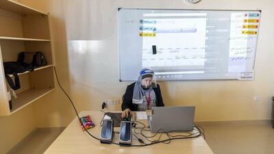 A teacher wears a face shield to stay safe.