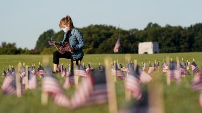 A volunteer places American flags representing some of the 200,000 lives lost in the United States in the coronavirus disease (Covid-19) pandemic on the National Mall in Washington, DC, USA. Reuters