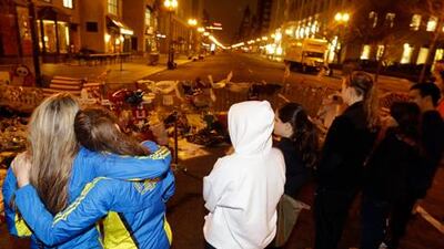 Two women pay respects at a makeshift memorial on Boylston Street near the finish line of the Boston Marathon. Julio Cortez / AP