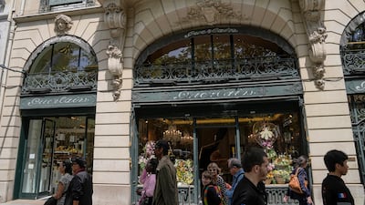People walk past the Guerlain boutique at the Champs-Elysees avenue in Paris