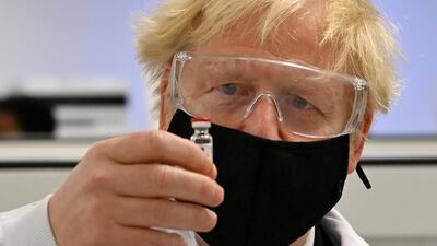 UK Prime Minister Boris Johnson looks at a vial of the AstraZeneca/University of Oxford vaccine against Covid-19. Reuters