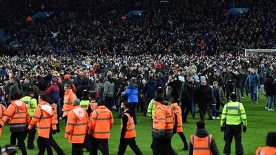 Police officers and stewards line the pitch as Aston Villa fans celebrate on the pitch. AFP