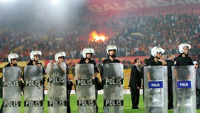 Riot police stand guard as the stands are set on fire by angry Galatasaray fans during a derby game against Fenerbahce.