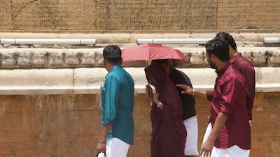 Tourists walk past granite walls with inscriptions