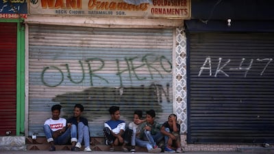 Kashmir boys sit in front of closed shops during restrictions in Srinagar. Reuters