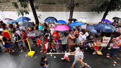 Residents holding umbrellas queue during a gift giving event on Christmas day in Las Pinas city, Philippines. EPA