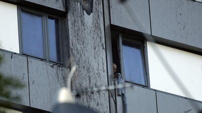 A person peers out of a window from a building on fire in London on June 14, 2017. Matt Dunham / AP Photo