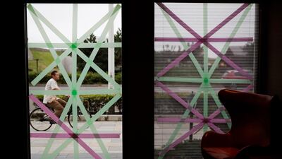 A man riding his bike is seen through a hotel window taped in preparation for Typhoon Hagibis in Kamakura, west of Tokyo. AP