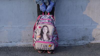 A girl holds a school backpack in her hands while wearing protective gloves in Bucharest, Romania. Reutes