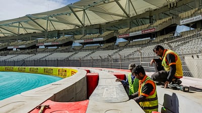 Workers ensure the circuit's safety barriers are up to muster