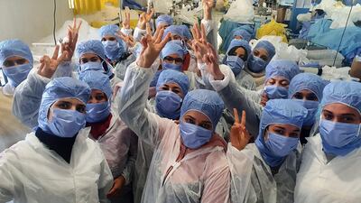 Tunisian women are working on the production of medical masks in a factory in the central city of Kairouan. The factory is able to continue production after 150 workers, seen cheering here, agreed to continue their tasks under confinement. AFP
