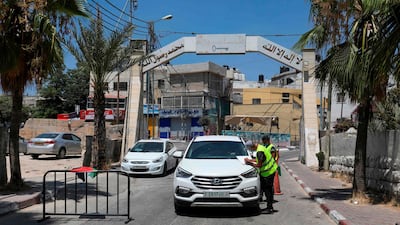 Palestinian volunteers check the temperature of a people in a car at the entrance of the Amari refugee camp near the West Bank city of Ramallah. AFP