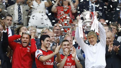 Arsene Wenger, right, hoists the FA Cup trophy after Arsenal defeated Hull City on May 17, 2014. It was the fifth time Wenger had won the trophy. Kirsty Wigglesworth / AP Photo
