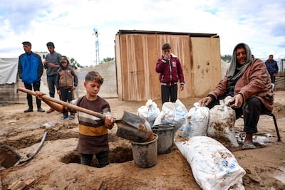 A child fills bags with sand to control flooding at a camp in Al Zaywayda in the central Gaza Strip. AFP
