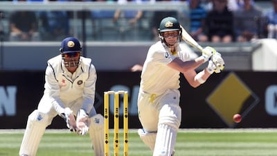 Australia batsman Steve Smith, right, prepares to hit a reverse sweep as India wicketkeeper MS Dhoni watches on during the second day of the third Test at the Melbourne Cricket Ground on December 27, 2014. William West / AFP