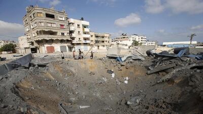 Palestinians stand next to a crater which police said was caused by an Israeli air strike in Gaza City on July 3, 2014. Israel struck over 15 Hamas targets in Gaza overnight in response to constant rocket fire launched from the Strip, the Israeli army said in a statement on Thursday. Mohammed Salem / Reuters