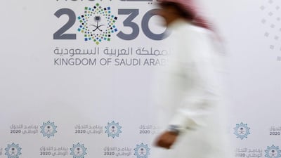 A Saudi man walks past the logo of Vision 2030 after last night's news conference, in Jeddah. Faisal Al Nasser / The National