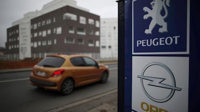 A Peugeot drives past the logos of French car maker Peugeot and German car maker Opel at a dealership in Villepinte, near Paris, France. RChristian Hartmann / Reuters