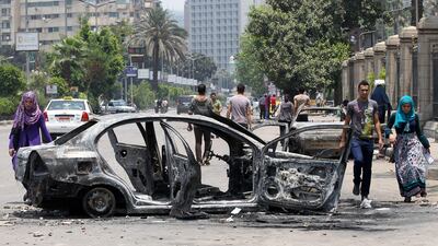 epa03772684 Egyptians look at a burnt out car after overnight clashes outside the Cairo University involving supporters of President Mohamad Morsi, Cairo, Egypt, 03 July 2013. Sixteen people were killed and at least 200 injured in the clashes, the Egyptian Health Ministry said. Pro-Morsi demonstrators had gathered in the area around the university in response to protests demanding that the president step down. EPA/KHALED ELFIQI *** Local Caption *** 03772684.jpg