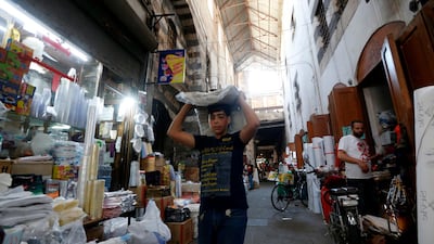 A Syrian boy carrying textiles is picture in the bazaar in old Damascus, on June 16, 2020. The Caesar Syria Civilian Protection Act of 2019, a US law that aims to sanction any person who assists the Syrian government or contributes to the country's reconstruction, is to come into force on June 17. / AFP / LOUAI BESHARA
