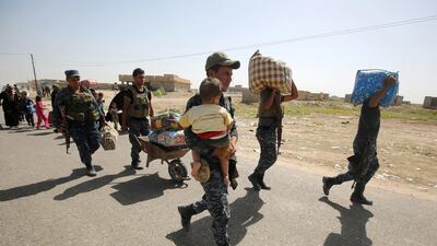 Iraqi government forces help people fleeing the fighting during an offensive to retake Fallujah from ISIL in June. Now an impending assault to recapture the city of Mosul has driven thousands of civilians to cross into Syria. Ahmad Al Rubaye / AFP / June 3, 2016
