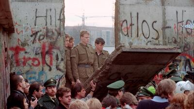 East German border guards are seen through a gap in the Berlin wall after demonstrators pulled down a segment of the wall at Brandenburg gate, Berlin. AP Photo