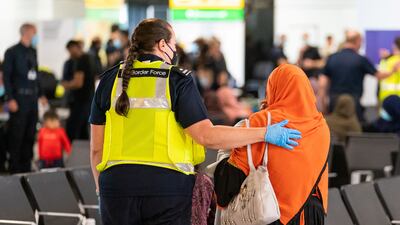 A member of Border Force staff assists a female evacuee as refugees arrive from Afghanistan at Heathrow Airport in August 2021. Reuters