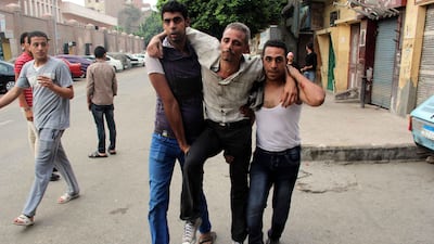 Two men help and injured protester. At least 23 people were killed in Cairo on Tuesday and over 200 others were injured. Mohammed El Shahed / AFP Photo