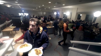 Main picture, a refugee walks to the camp at the hotel said to be the world’s most northerly ski resort. Above, displaced migrants at a dining room. Below, a refugee clears snow at the entrance of the camp.