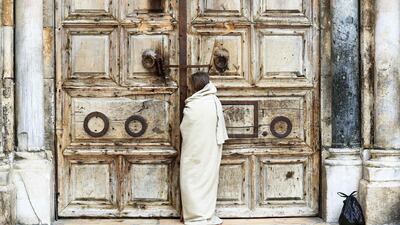 A Christian pilgrim dressed as Jesus Christ stands in front of the closed door of the Holy Sepulchre Church in Jerusalem's Old City. AFP