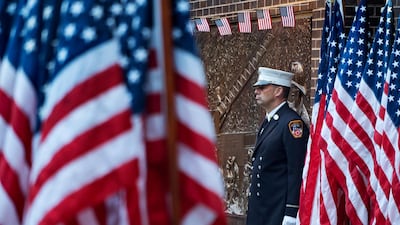 A New York City firefighter stands at attention by a memorial at the side of a firehouse adjacent to One World Trade Center and the 9/11 Memorial site. AP Photo