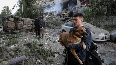A resident carries his pet to safety at the site of a missile and drone strike on Kyiv on June 2. Reuters